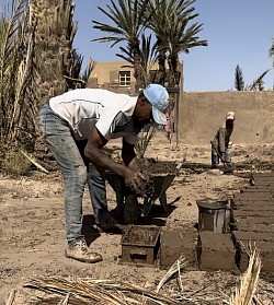 Mohamed and his brother shaping earth bricks, heirs to an ancestral know-how.